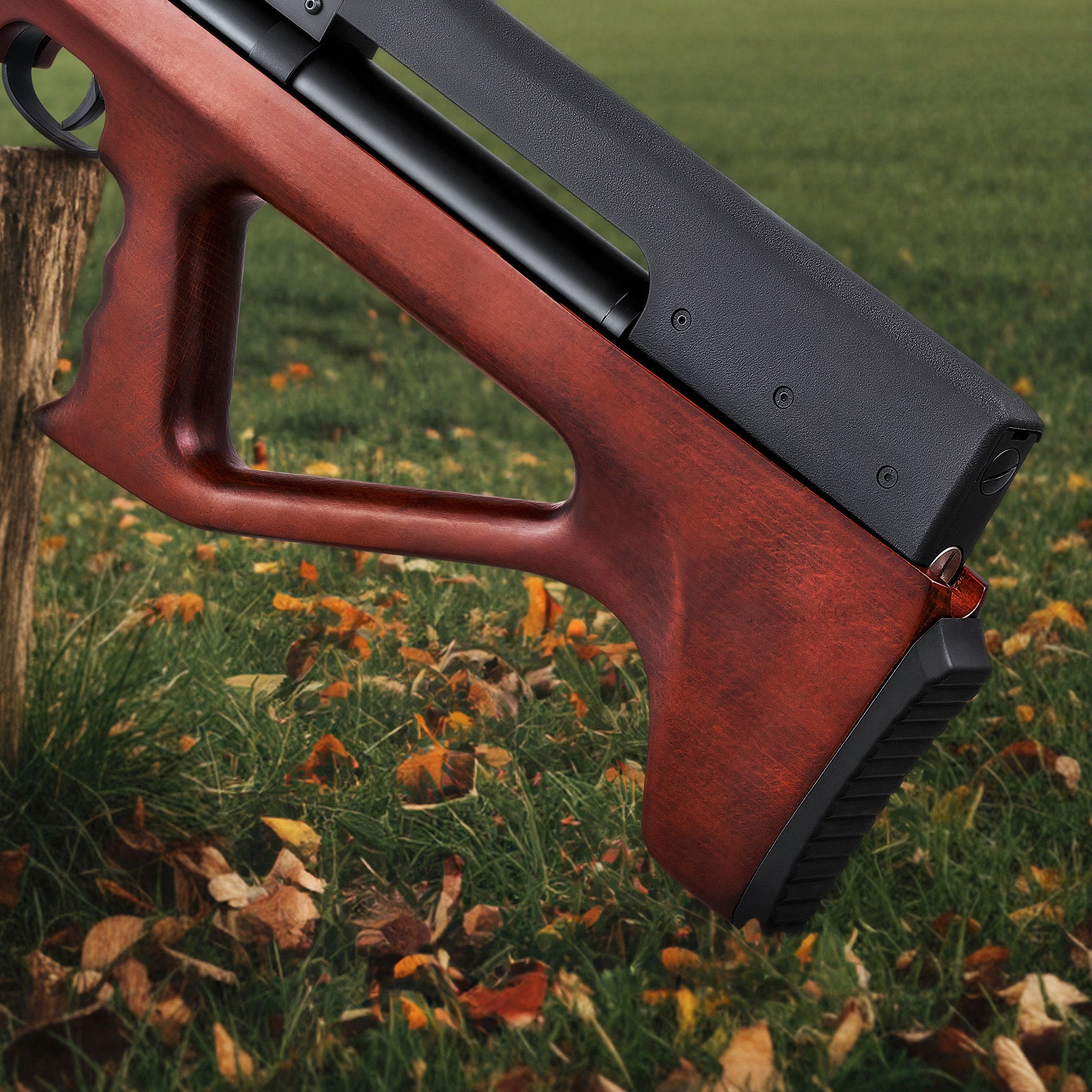Red and black rifle on a grassy background with leaves