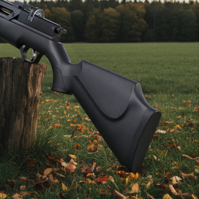 Black rifle leaning against a tree stump in a grassy field with trees in the background